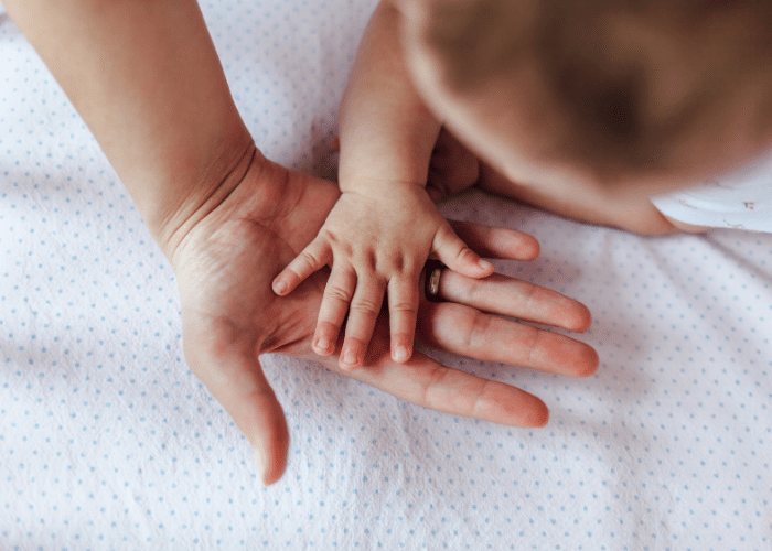 Baby placing hand on parents' hand on white background