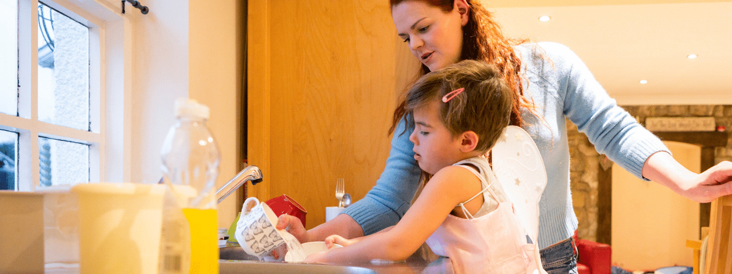 Child in dress does dishes with parent